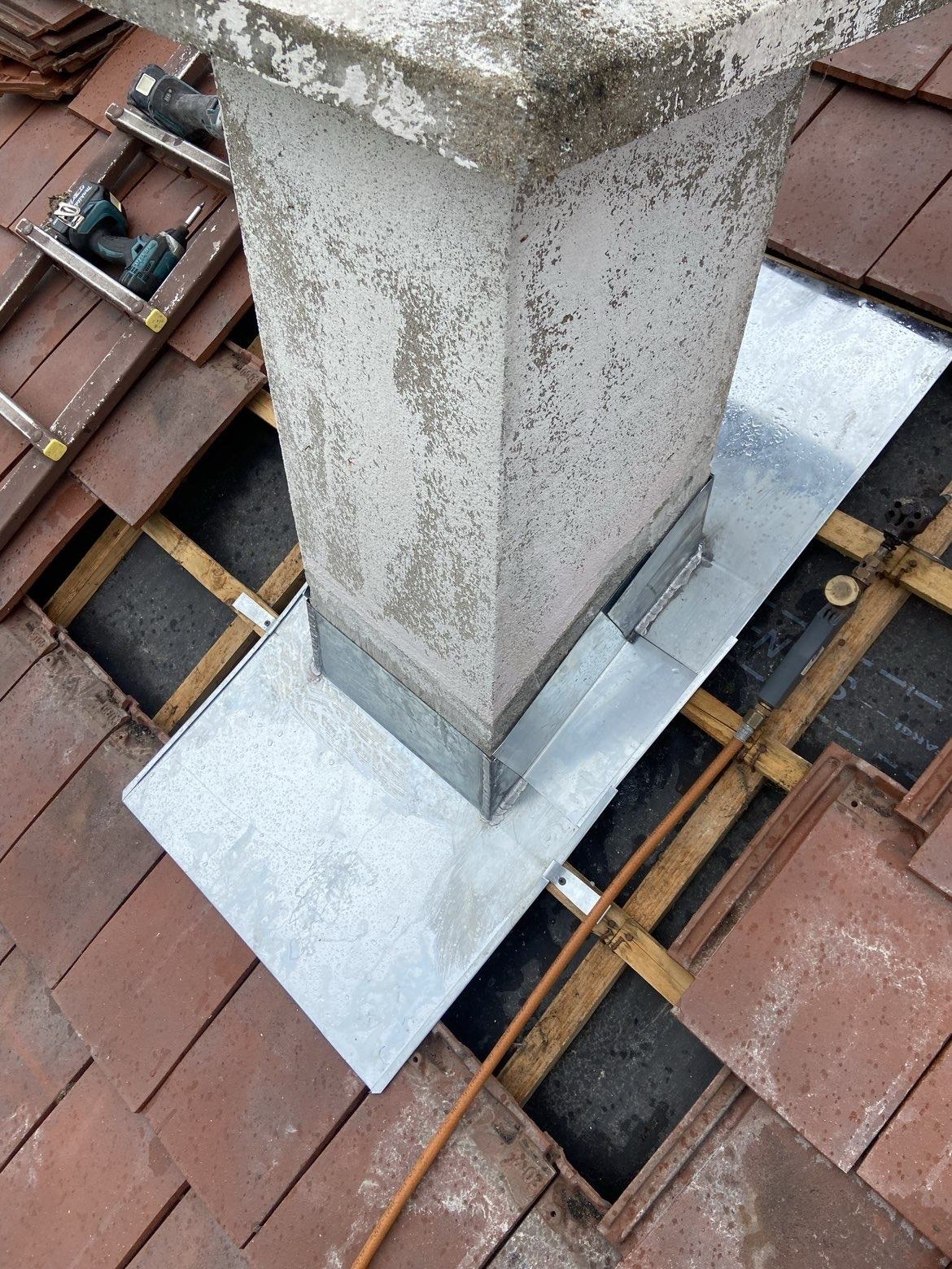 Bavette zinc en cours de pose autour d’une cheminée sur toiture en tuiles plates
